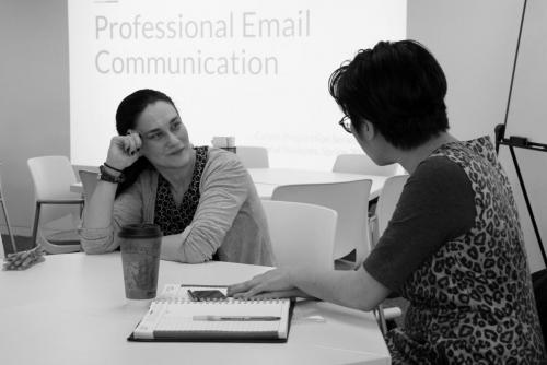 Sheridan staff and student talking in a classroom with a Powerpoint slide reading "Professional Email Communication" in the background