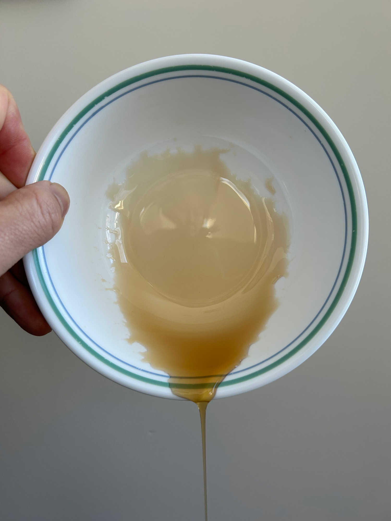 a bowl with a thin film of brown liquid slowly pouring out